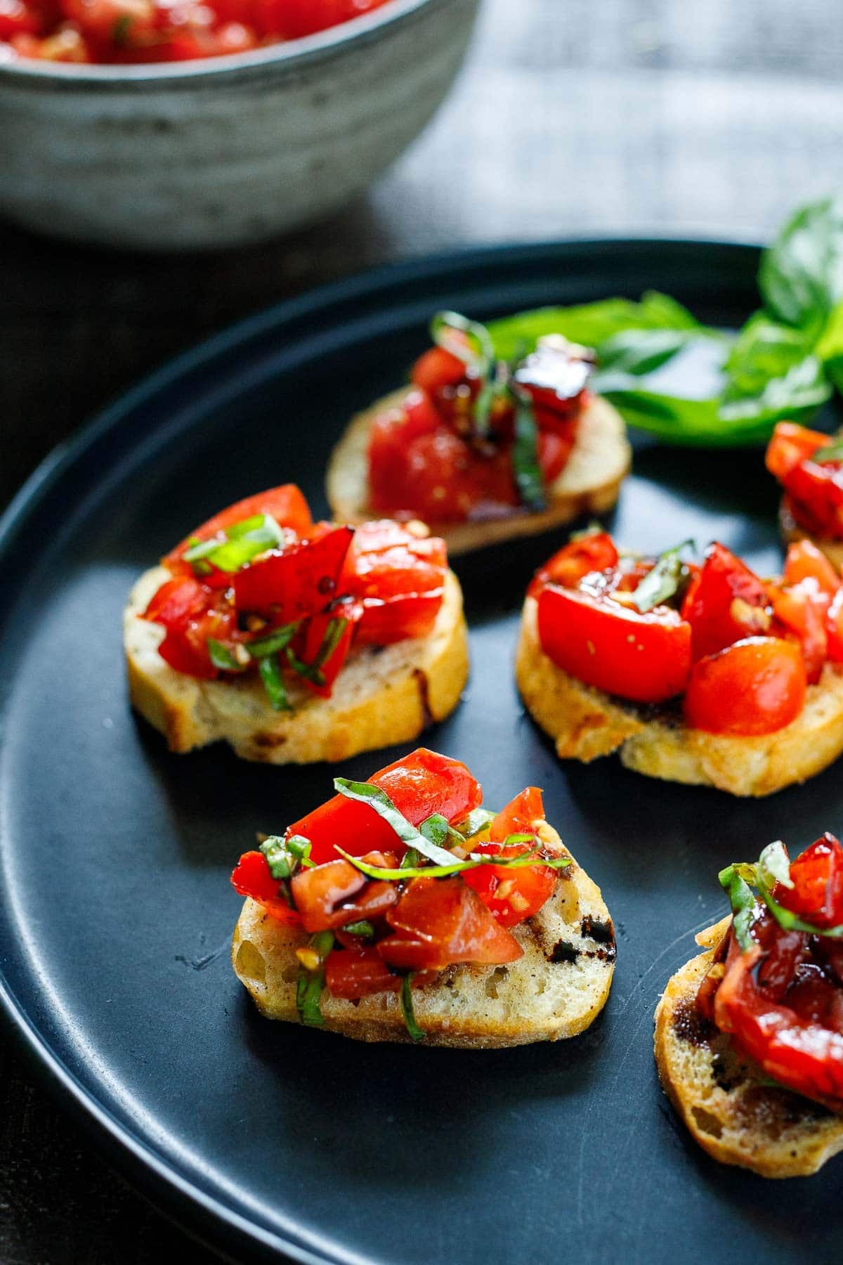 tomato bruschetta on a small platter with a drizzle of balsamic glaze