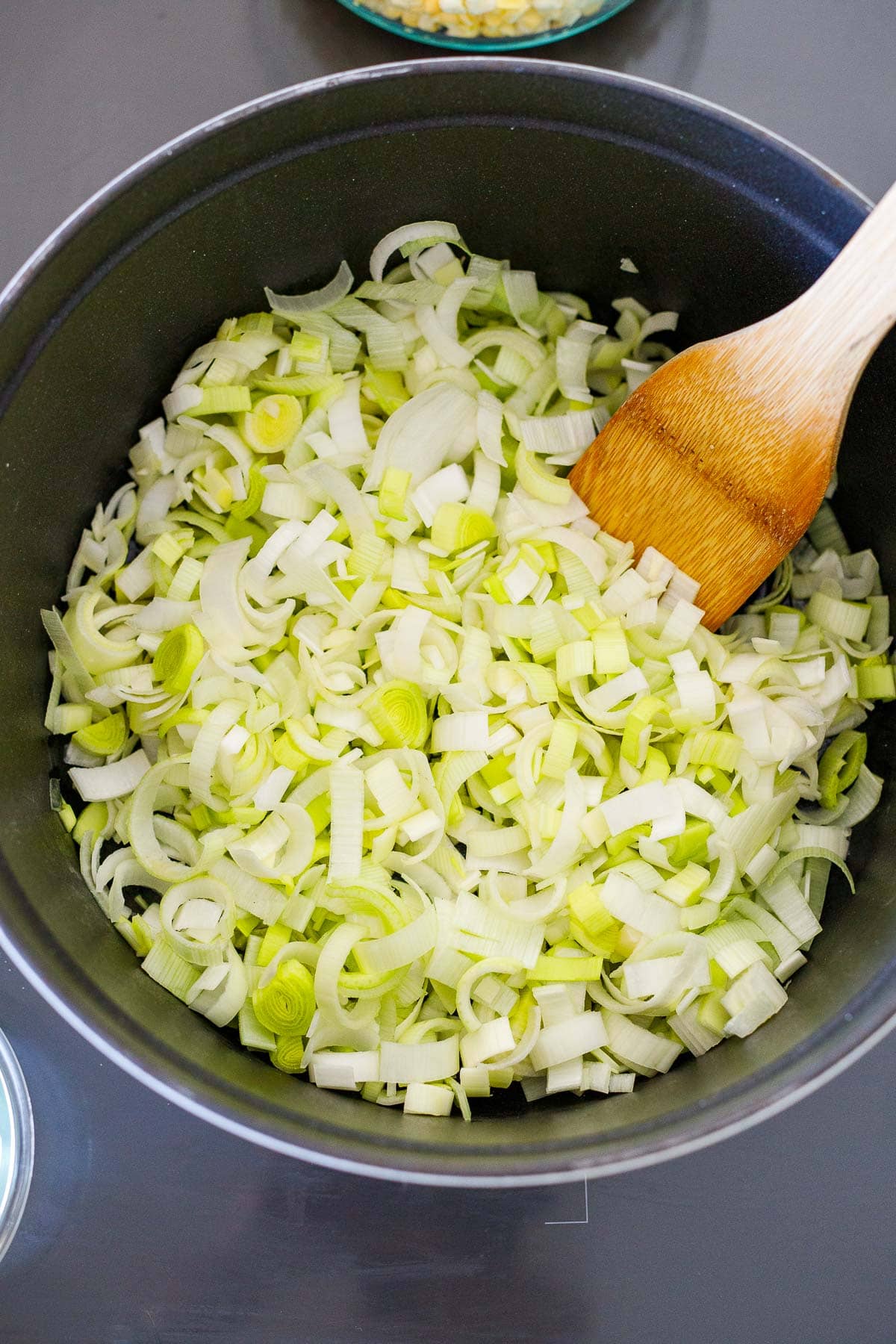 pot with sliced leeks and a wooden spatula.