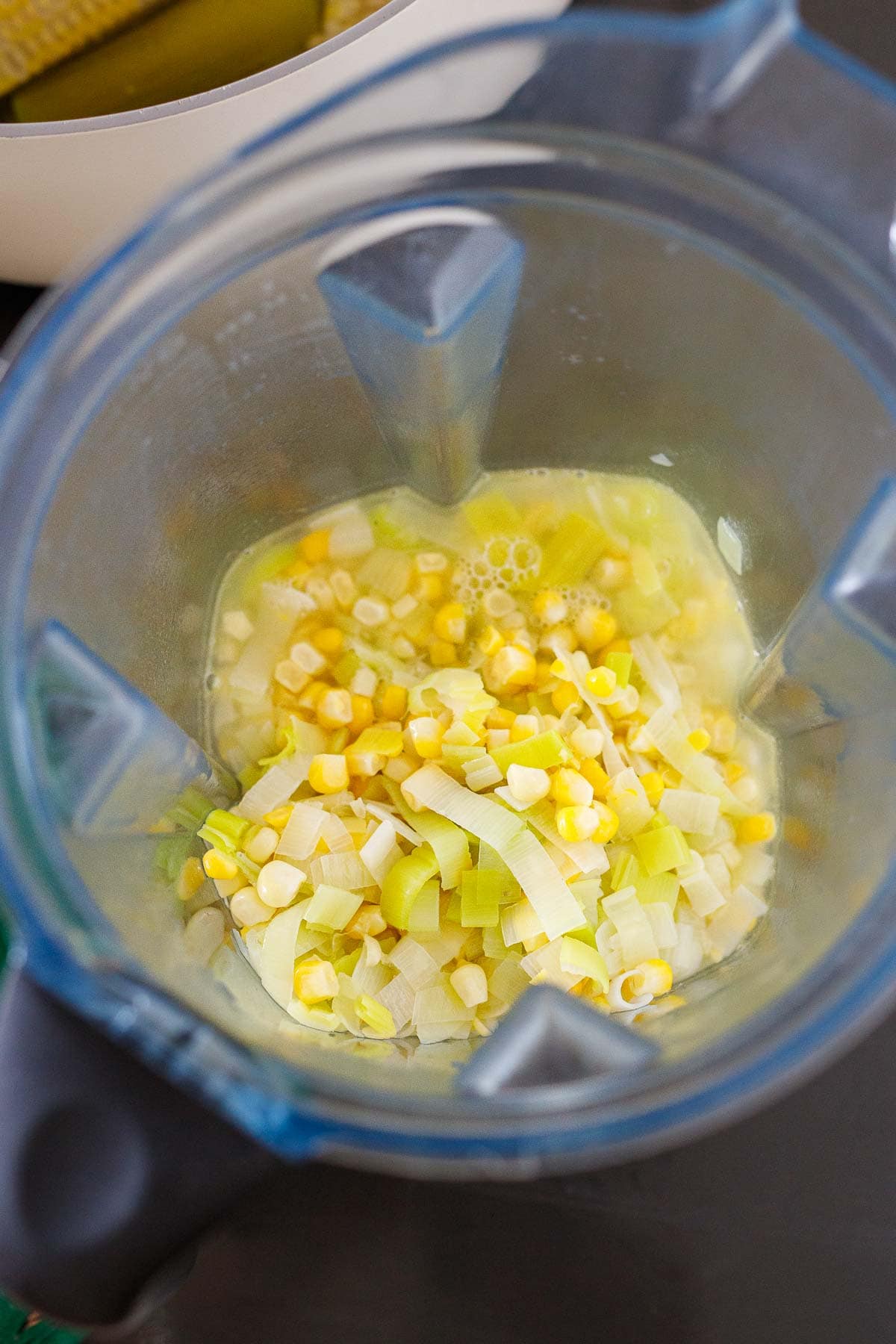 blender with corn, leeks, and broth added to it.