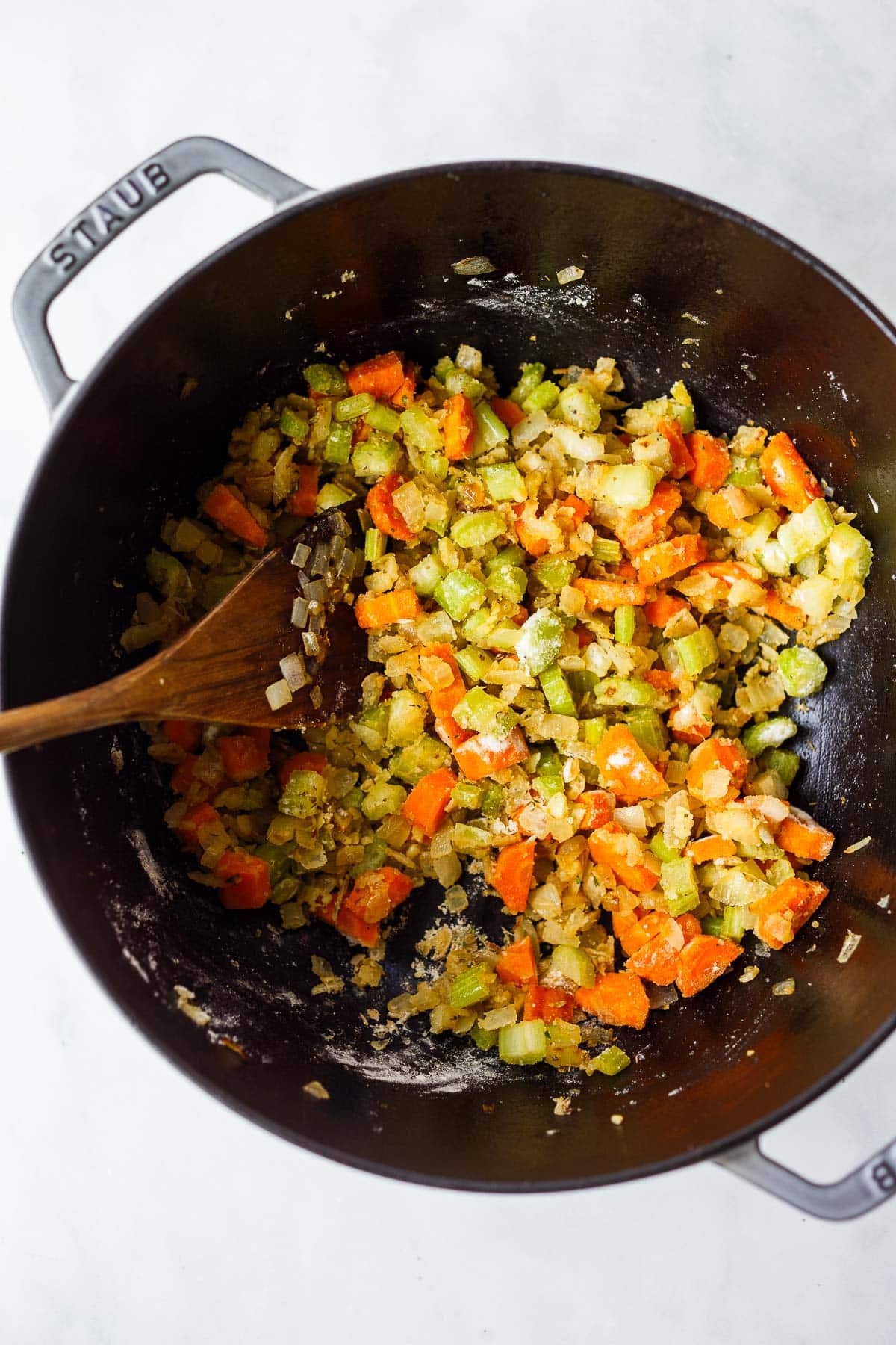 dutch oven with sautéed veggies tossed in flour, forming the base for creamy chicken noodle soup.