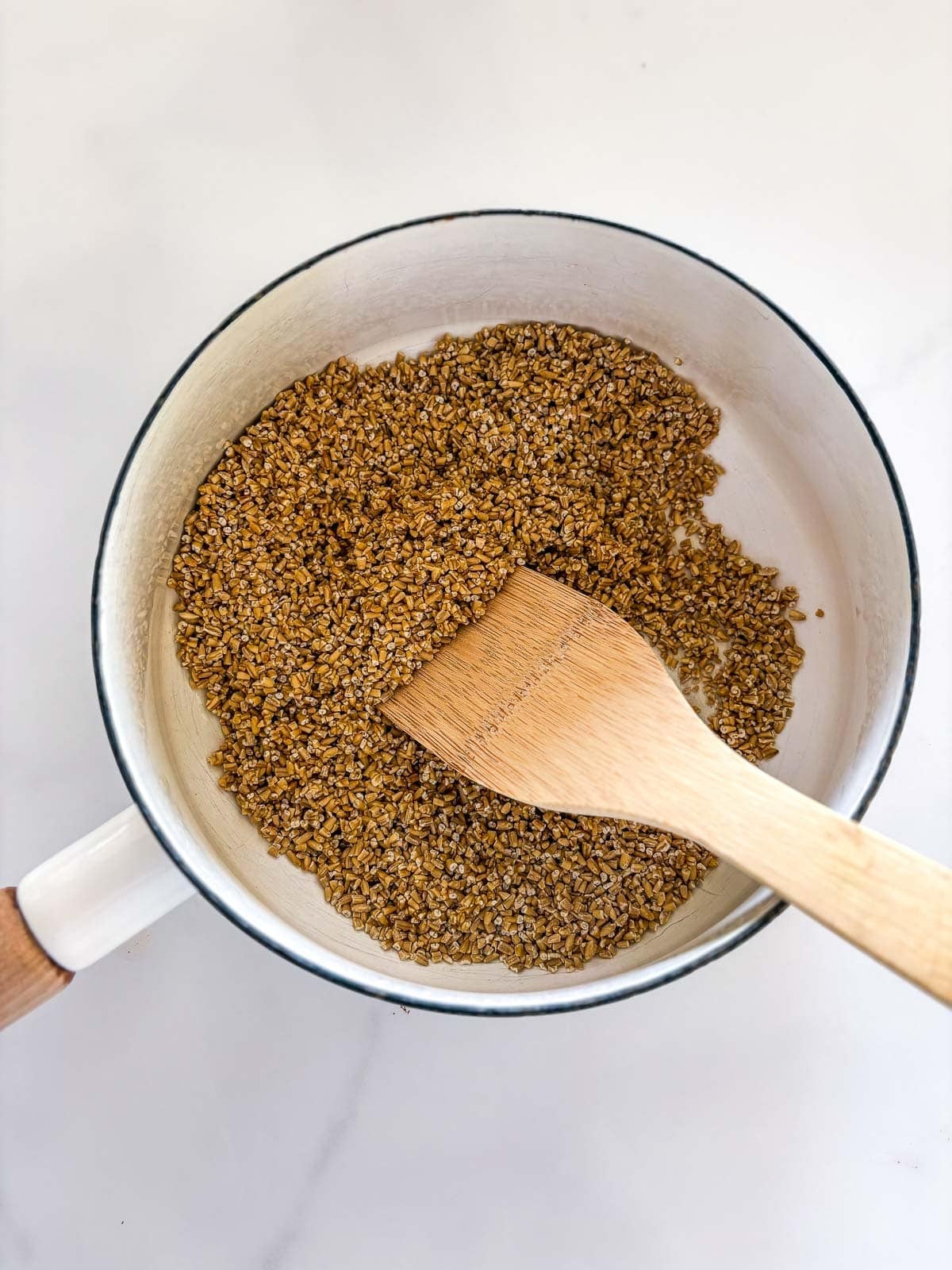 toasting steel cut oats in a saucepan with a wooden spatula.