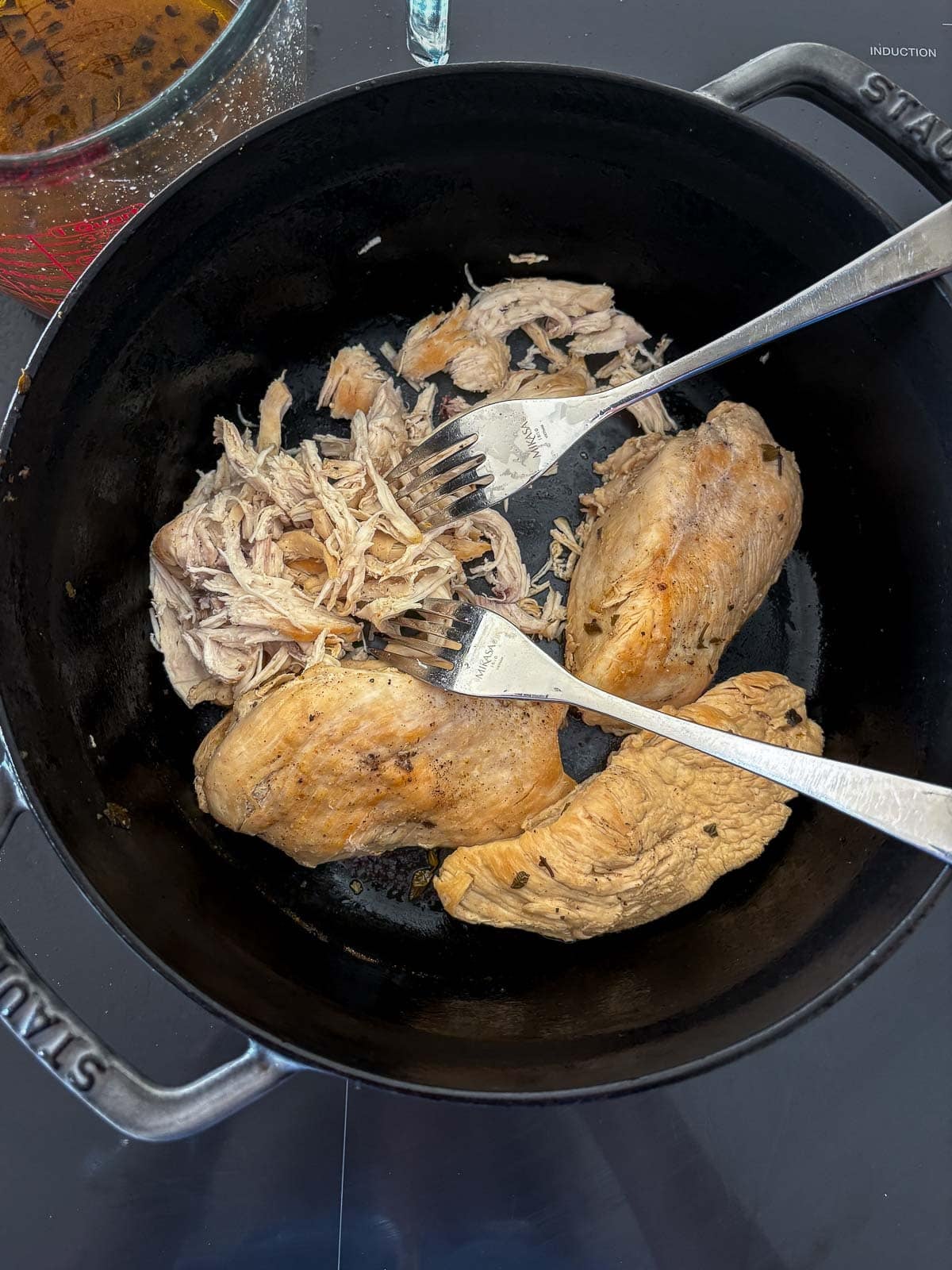 seared chicken in a pot with two forks to make shredded chicken.