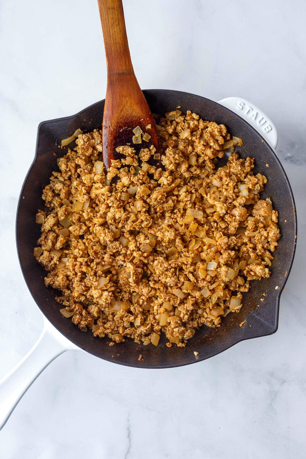 ground chicken in a skillet with onions and spices.