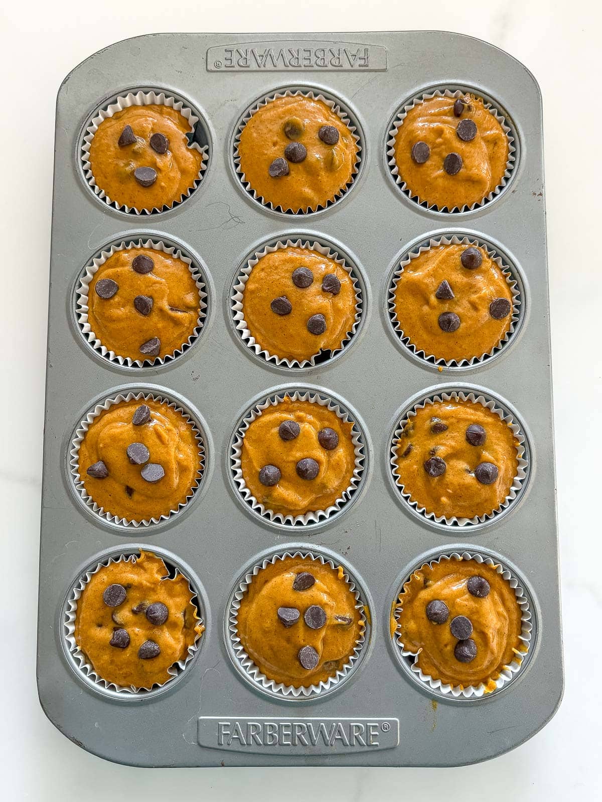 Unbaked pumpkin muffins in muffin tins.